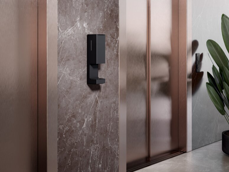 Een aanraakvrije dispenser voor ontsmettingsmiddelen is geïnstalleerd op de muur tussen twee liftdeuren